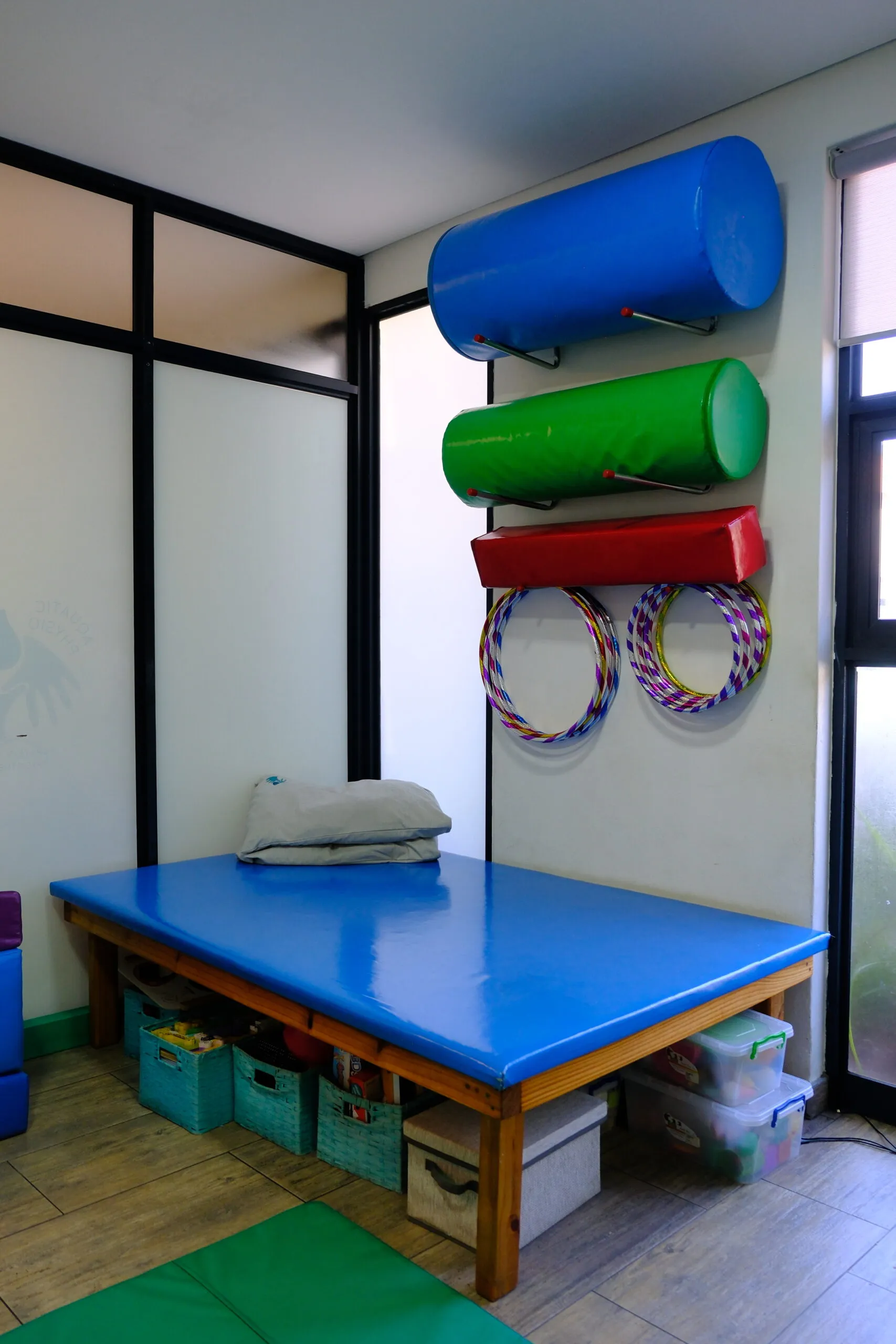 Paediatric treatment room — wall-mounted rolls, hoops and a padded table for MAES and NDT sessions.